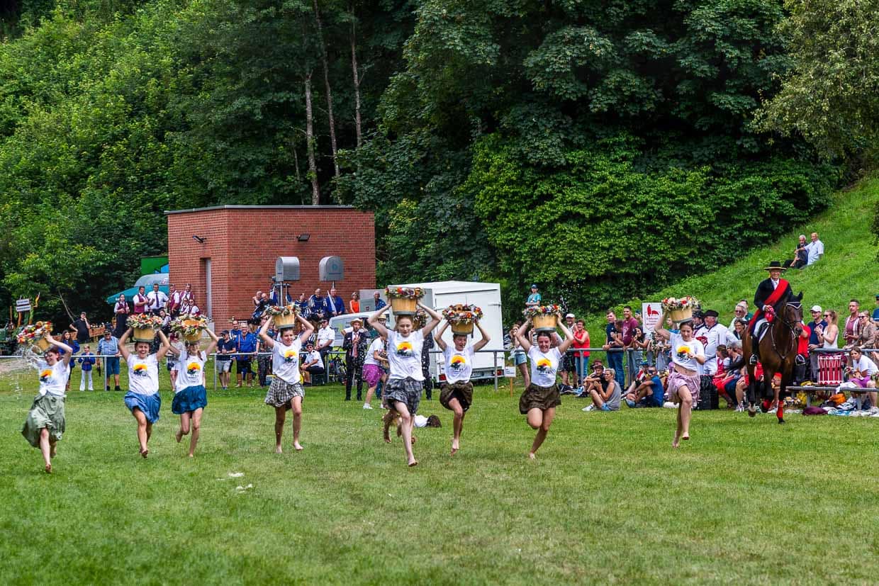 Schülerinnen beim Wasserkübellauf. Bei dem Lauf treten junge Frauen der neunten und zehnten Klasse des Bildungszentrums Wildberg mit Wasserkübeln auf dem Kopf in einem Wettlauf gegeneinander an. Dieser Lauf ist ein fester Bestandteil des Schäferlaufs und symbolisiert die früheren Aufgaben der Schäfermädchen und -frauen, die Wasser für Mensch und Tier herantragen mussten. Er erinnert an die harte körperliche Arbeit und das Geschick, das im Alltag der Schäferei notwendig war / © Foto: Georg Berg