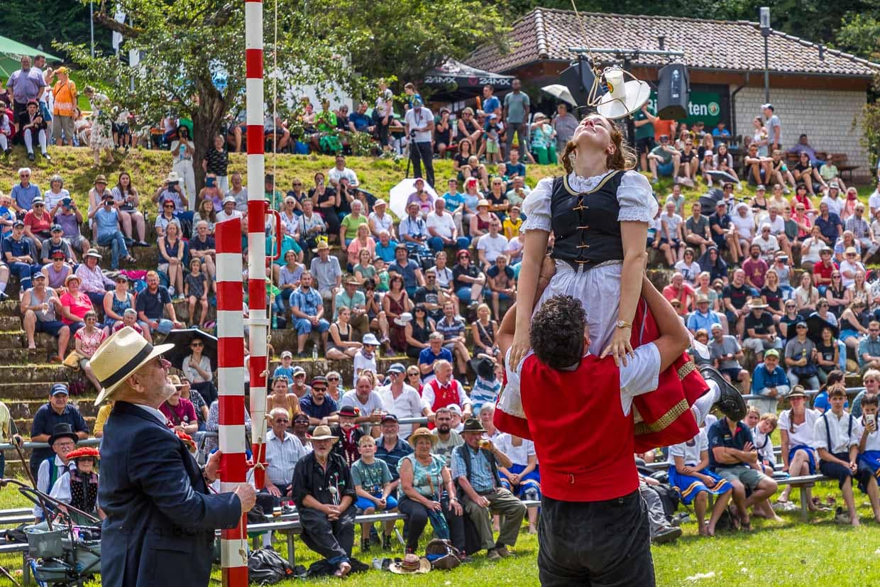 Ein Paar beim Hahnentanz auf dem Schäferlaufplatz in Wildberg. Der Tanz ist ein fester Bestandteil des Rahmenprogramms. Der Hahnentanz ist ein symbolisches Spiel, das auf die früher verbreitete Praxis des „Hahnenköpfens“ zurückgeht, bei dem ein lebender Hahn das Ziel war. Im Zuge der Entwicklung des Tierschutzes wurde diese Praxis durch das harmlosere Wasserglas ersetzt. Wer das Glas durch das Anheben des Partners erfolgreich vom Brett stößt, gilt als Sieger des Spiels / © Foto: Georg Berg