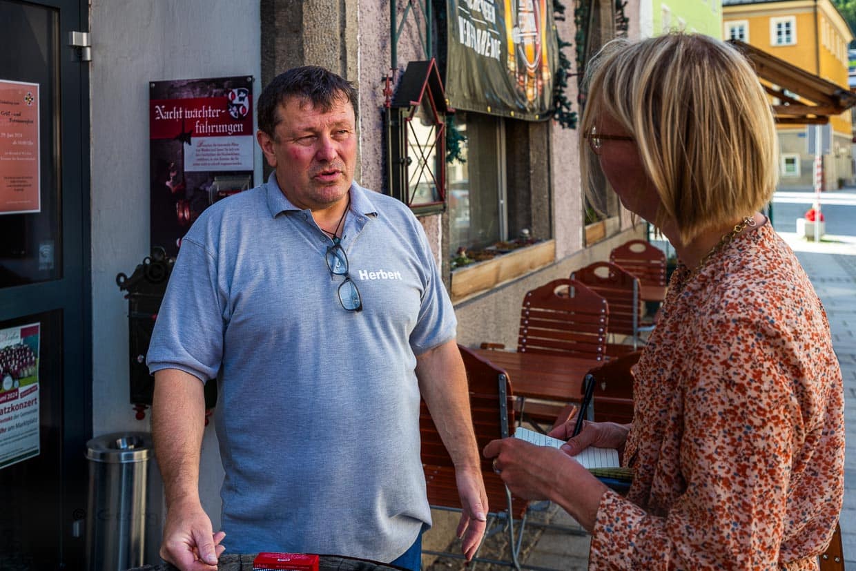 Reisejournalistin Angela Berg im Gespräch mit Herbert Haas, Betreiber der Gaststätte Burgschänke sowie Nachtwächter und Stadtführer in Werfen. Rund 300.000 Touristen, davon 10 Prozent Amerikaner und Japaner, besuchen jedes Jahr den kleinen Ort im Salzburger Land. Grund ist der Sound of Music-Trail / © Foto: Georg Berg