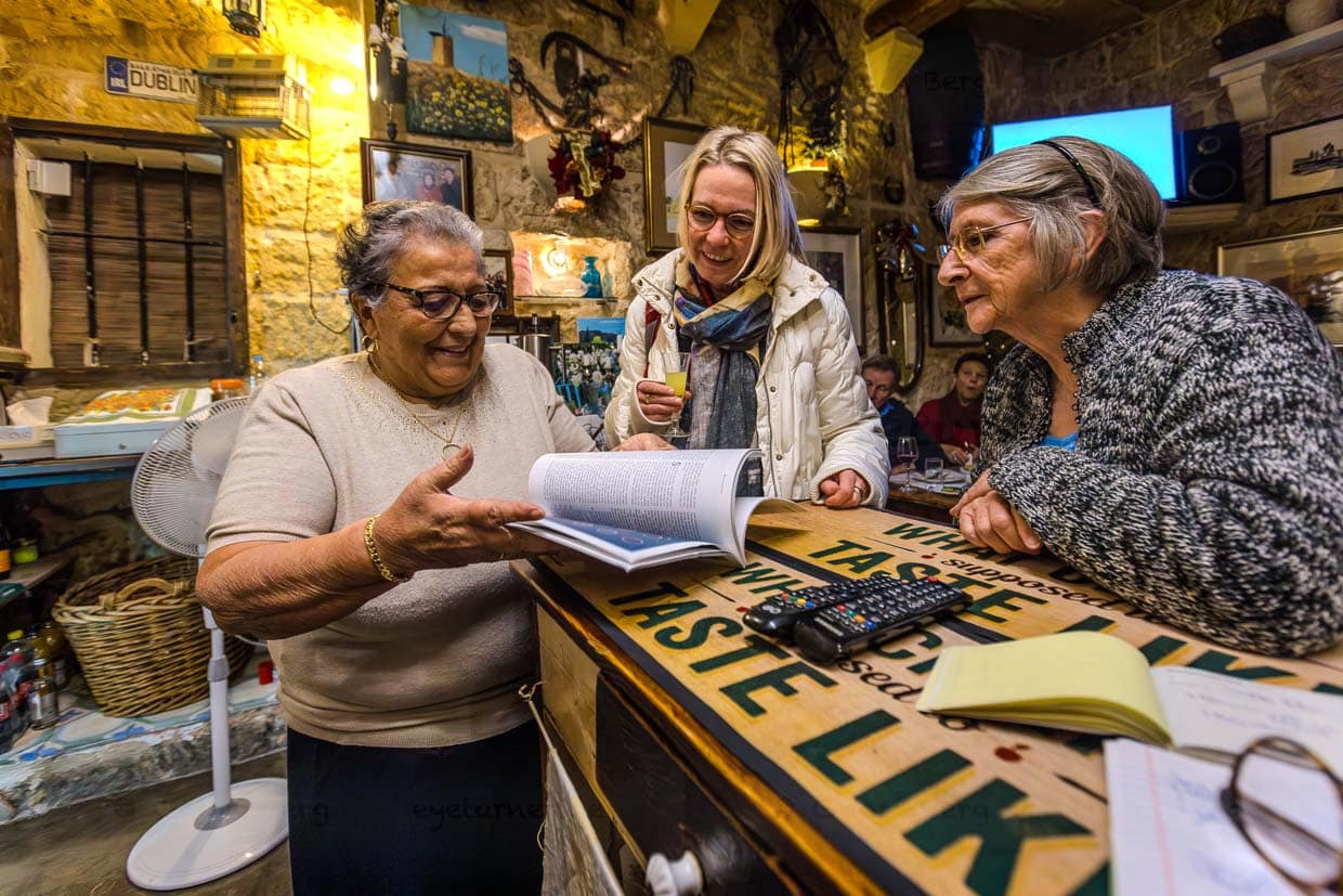Rosina Tabone mit Gästen an der Theke ihres Restaurants. Der Raum hat nur wenige Tische und ist bei Dorfbewohnern und Gästen aus Malta beliebt für die traditionell gekochten Nationalgerichte Fenek (Kanninchen) und Lampuki (Goldmakrele) / © Foto: Georg Berg