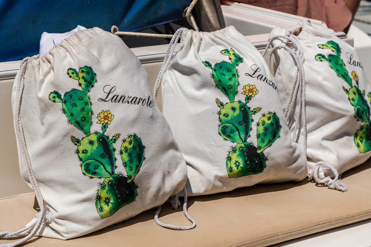 Taschen mit Cochenille-Lanzarote-Motiv auf einem Boot vor Lanzarote / © Foto: Georg Berg