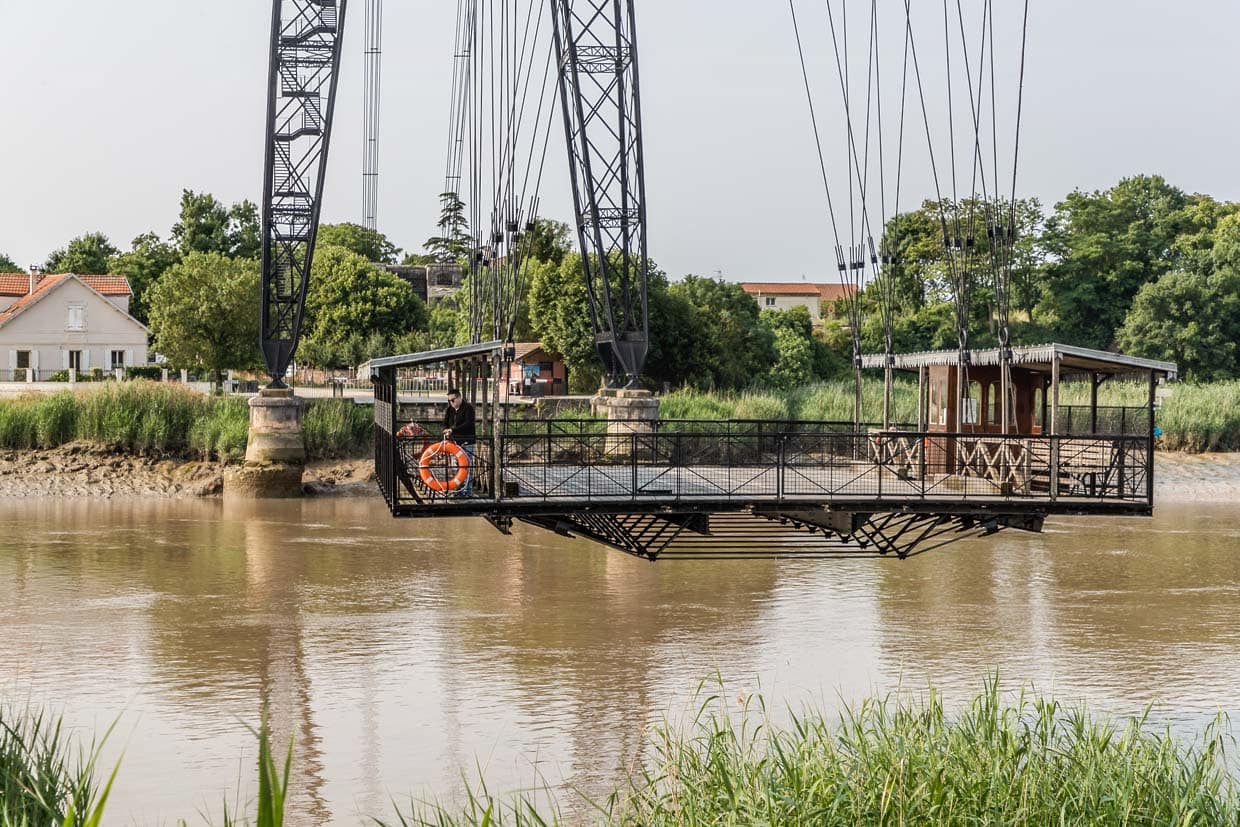 An den Trägern hängt eine Gondel (Schwebefähre), mit der Fußgänger und Radfahrer den Fluss überqueren können. Damit wird der Schiffsverkehr unter der Brücke nicht beeinträchtigt. Eine Überfahrt dauert 75 Sekunden / © Foto: Georg Berg