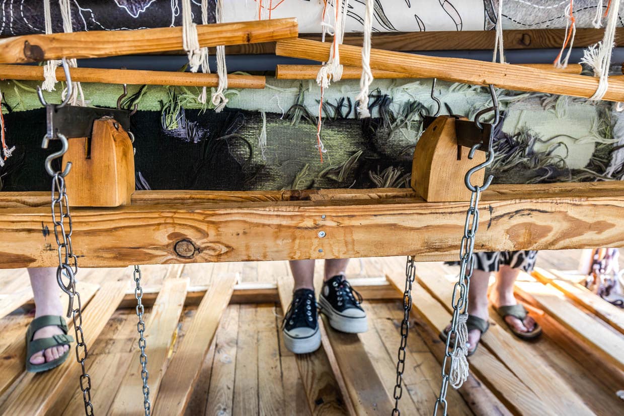 Blick unter den Flachwebstuhl (Basselisse), auf dem drei Weberinnen des Ateliers Robert Four aus Aubusson den Wandteppich "Hommage à George Sand" von Françoise Petrovitch anlässlich des 150. Todestags von George Sand fertigen. Die fertiggestellten Passagen des 23 Meter langen Teppichs rollen sich wieder auf und sind nur von der Hinterseite zu sehen. Das vollständige Werk wird auch für die Weberinnen erst am Tag des Ablösens aus dem Webstuhl zu sehen sein / © Foto: Georg Berg