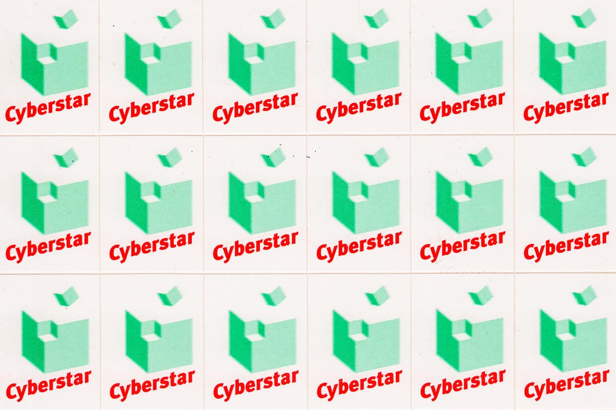 Cyberstar-Logo:Cyberstar-Schriftzug und grüner Würfel, aus dessen Ecke ein kleiner grüner Würfel davonfliegt