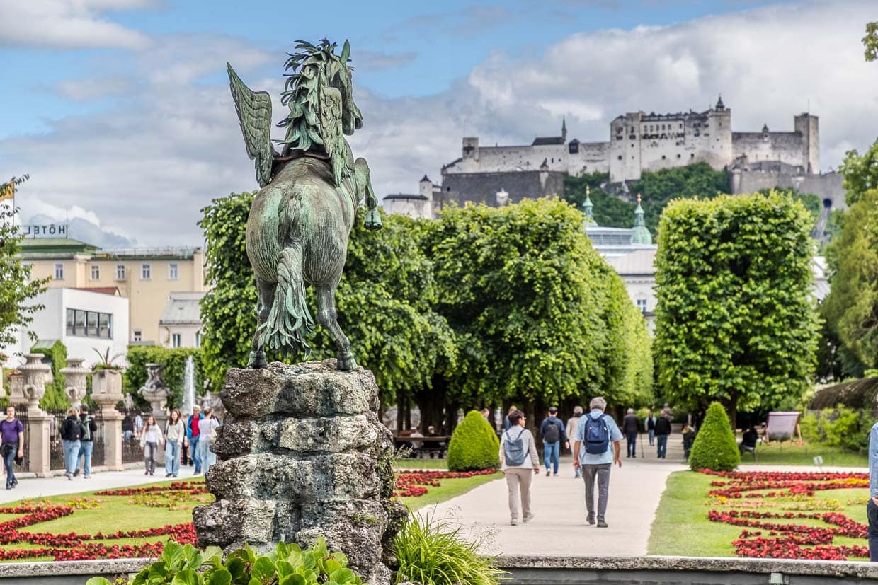 Eine Pegasus-Bronzestatue überblickt Spaziergänger und die Festung Hohensalzburg am Bernhard-Paumgartner-Weg, Salzburg, Austria