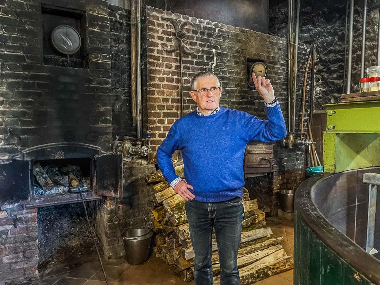 Francois Tonglet, Bierbrauer und Eigentümer der Brasserie Caracole in Falmignoul erläutert den Brauprozess mit Holzfeuer, Kupferkessel. Seit 1765 wird hier Bier gebraut / © Foto: Angela Berg