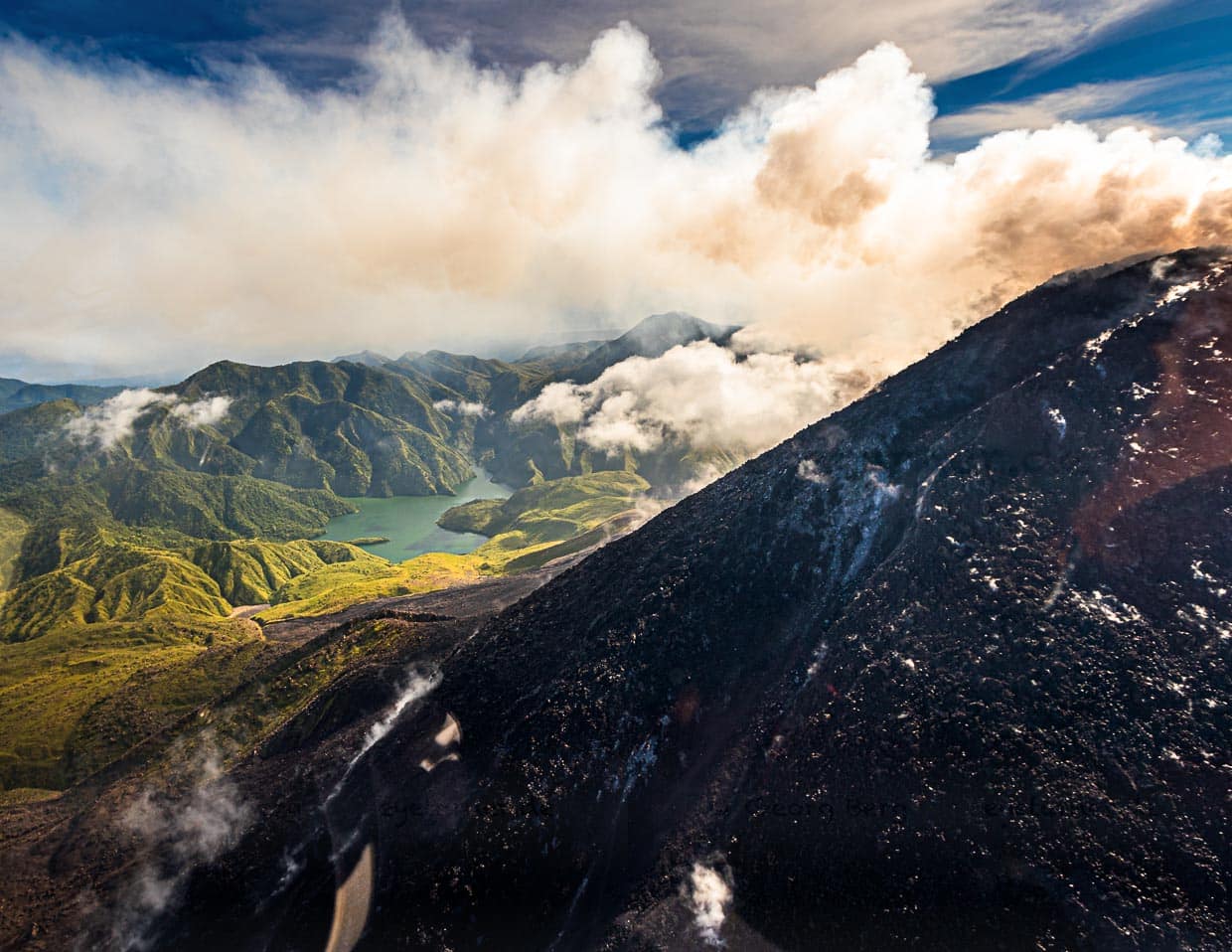 Hinter dem aktiven Bagana Vulkan taucht die mit Wasser gefüllte Formation des Lake Billy Mitchell auf / © Foto: Georg Berg