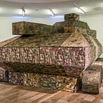 Krieg – immer wieder ein Thema auf der documenta. Sitzmodule in Fleckentarnung werden zweimal in der Woche in einer Performance zu einem Panzer in Originalgröße zusammengebaut / © Foto: Georg Berg