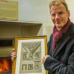 Matthias Trum von der Schlenkerla Bräu vor dem Holzofen mit dem das Grünmalz betrocknet wird. In der Hand hält er eine Zeichnung zur industriellen Malztrocknung nach Sir Nicholas Halse / © Foto: Georg Berg