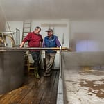 Kurz bevor sich das Brauhaus mit dichtem Nebel füllt steht Zoigl-Braumeister Sepp Neuber mit einem Hausbrauer am Schiff / © Foto: Georg Berg