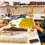 Am kühlen Vormittag wird der Bestseller der Schokoladen-Manufaktur Frigoulette von Hand in goldenes Papier verpackt. Malakoff-Pralinen, Nuss-Nougat-Pralinen mit 68  Kakaoanteil und gerösteten Haselnüssen. Im Sommer läuft die Produktion für Weihnachten. Frigoulette beliefert Geschäfte in ganz Frankreich mit Malakoff-Pralinen / © Foto: Georg Berg