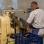 Maschinelle Verpackung von Nuss-Nougat-Pralinen in gold und rot gesteiften Papilloten in der Chocolaterie Frigoulette in Beaufort-sur-Gervanne im Val de Drôme / © Foto: Georg Berg