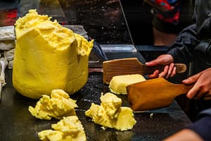 Die Butterstücke werden mit zwei Holzpaddeln geschlagen bis Wasser austritt. Die Butter beginnt zu weinen / © Foto: Georg Berg