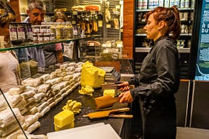 Verkaufstheke im Maison du Beurre von Jean Yves Bordier in Saint Malo. Eine Verkäuferin schlägt die Butter mit zwei Holzpaddeln / © Foto: Georg Berg