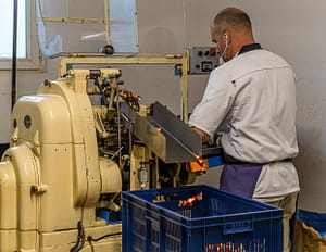 Maschinelle Verpackung von Nuss-Nougat-Pralinen in gold und rot gesteiften Papilloten in der Chocolaterie Frigoulette in Beaufort-sur-Gervanne im Val de Drôme / © Foto: Georg Berg