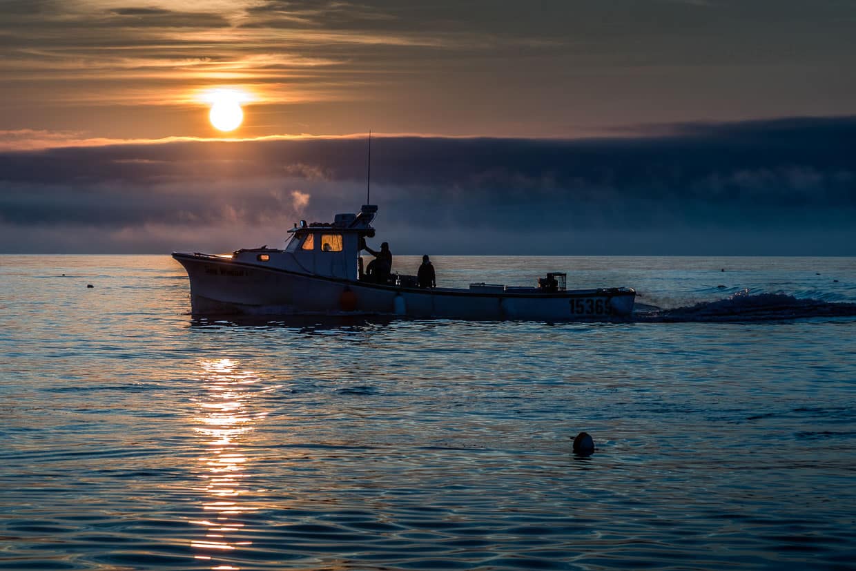 Fischerboot fährt bei Sonnenaufgang auf dem Meer vor Indian Brook, Canada