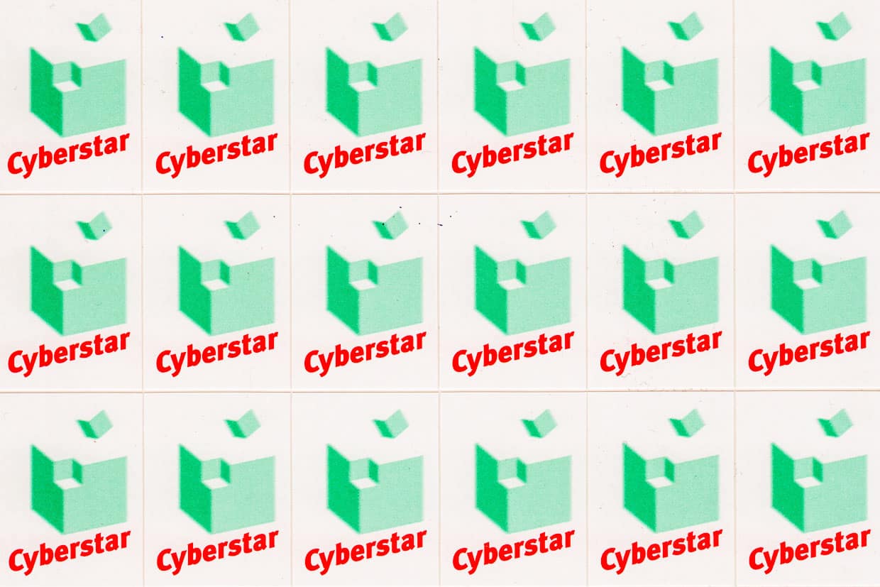 Cyberstar-Logo:Cyberstar-Schriftzug und grüner Würfel, aus dessen Ecke ein kleiner grüner Würfel davonfliegt