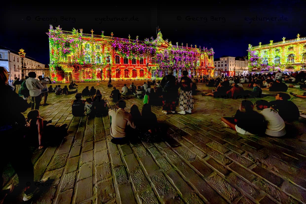 Menschen beobachten eine Lichtshow auf dem Place Stanislas in Nancy, Frankreich