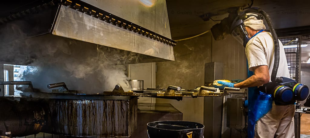 Der Mitarbeiter, der die Käse auflegt, bekommt Frischluft über einen Spezialhelm / © Foto: Georg Berg