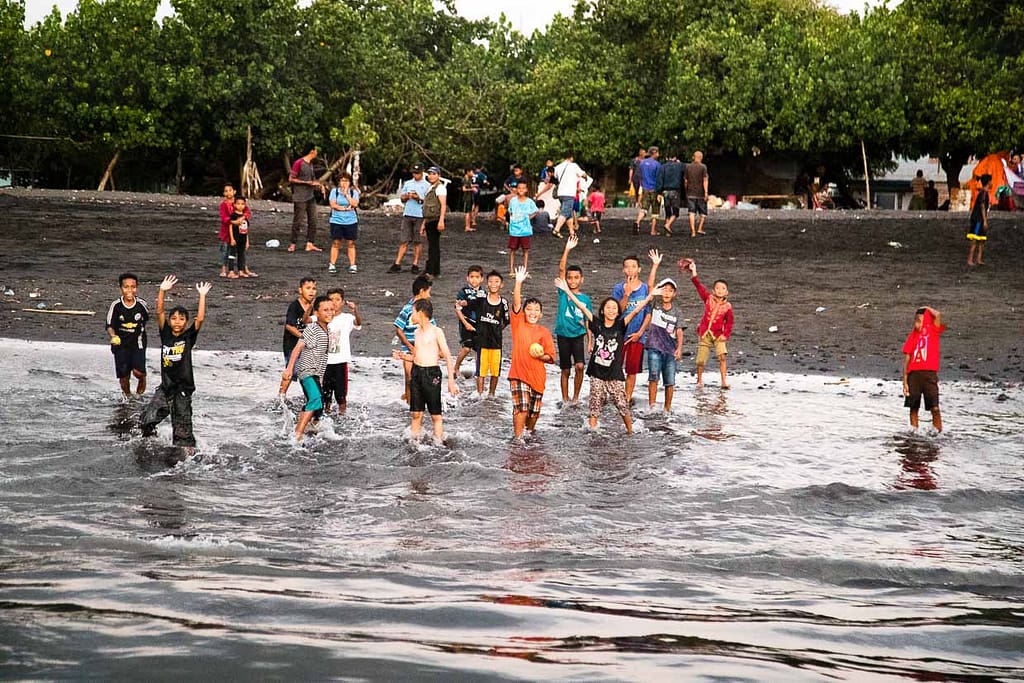 Kinder winken am Strand im ländlichen Indonesien / © Foto: Georg Berg