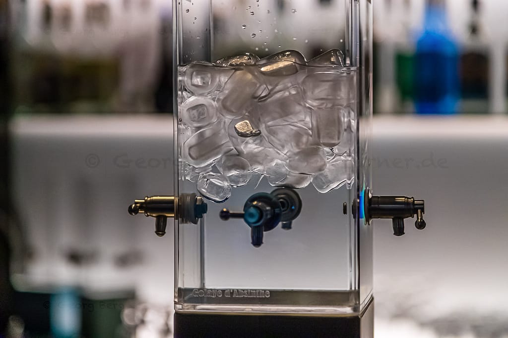 Moderne kalte Quelle für Absinth. Früher tropfte das eiskalte Wasser mit einem Tropfen pro Minute über den Zuckerwürfel und durch den Löffel in den zimmerwarmen Alkohol. Jeder Tropfen hinterließ eine milchig-grüne Trübung im Glas / © Foto: Georg Berg