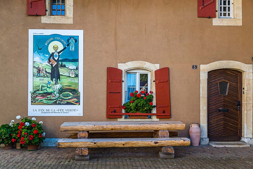 Absinth in Frankreich und der Schweiz. In Motiers im Schweizer Kanton Neuchâtel befindet sich das unterhaltsame Absinthmuseum, und an einigen Häuserwänden der Stadt erinnern historische Plakate an die Zeit der Prohibition / © Foto: Georg Berg