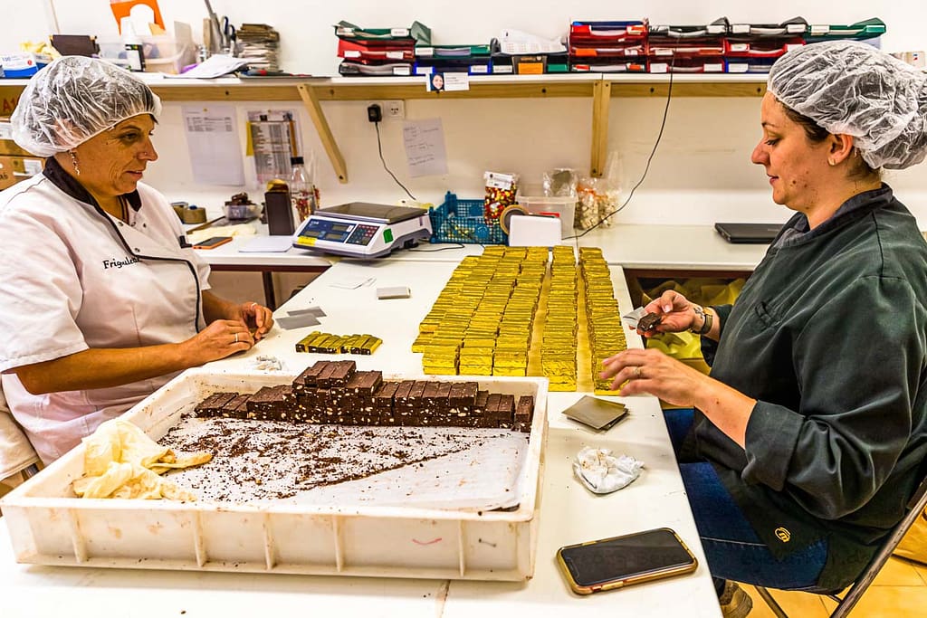 Am kühlen Vormittag wird der Bestseller der Schokoladen-Manufaktur Frigoulette von Hand in goldenes Papier verpackt. Malakoff-Pralinen, Nuss-Nougat-Pralinen mit 68  Kakaoanteil und gerösteten Haselnüssen. Im Sommer läuft die Produktion für Weihnachten. Frigoulette beliefert Geschäfte in ganz Frankreich mit Malakoff-Pralinen / © Foto: Georg Berg