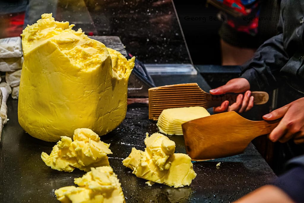 Die Butterstücke werden mit zwei Holzpaddeln geschlagen bis Wasser austritt. Die Butter beginnt zu weinen / © Foto: Georg Berg