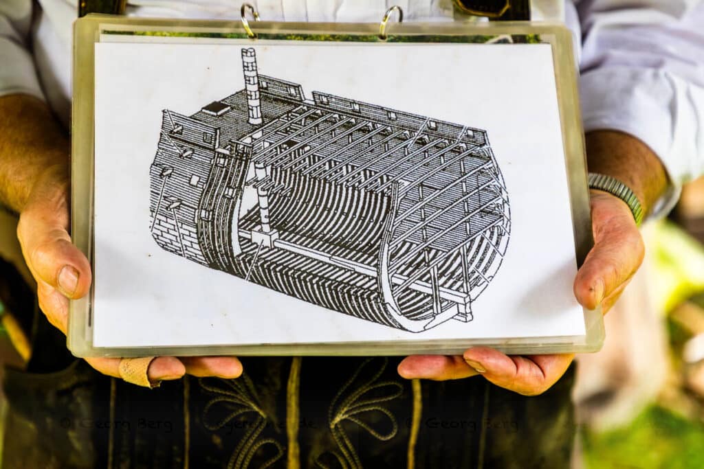 Flößer Martin Sprang zeigt Konstruktionszeichnungen, die im Wald zur Auswahl der Bäume verwendet werden konnten / © Foto: Georg Berg