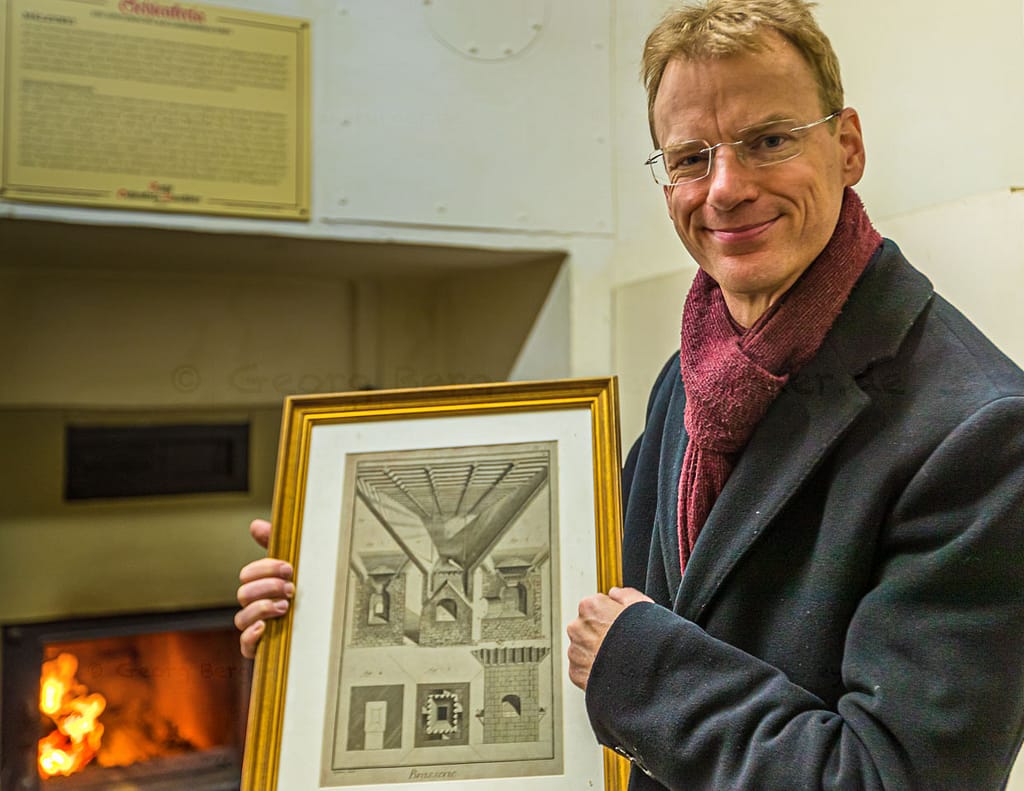 Matthias Trum von der Schlenkerla Bräu vor dem Holzofen mit dem das Grünmalz betrocknet wird. In der Hand hält er eine Zeichnung zur industriellen Malztrocknung nach Sir Nicholas Halse / © Foto: Georg Berg