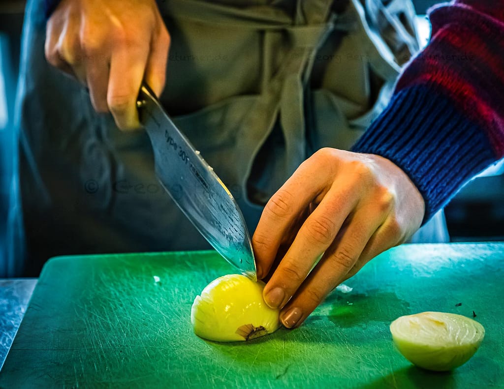 Laszlo Papdi macht das Kochmesser Chroma Type 301 fit für die erste Schneidübung. Der Klassiker steht an: die Zwiebel. Ob das Schneiden einer Zwiebel tränenreich oder tränenlos verläuft, hängt maßgeblich von der Schneidetechnik und der Schärfe eines Messers ab / © Foto: Georg Berg