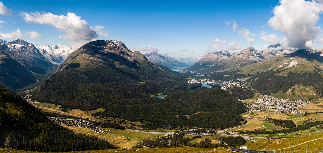 Aussicht von der Bergstation Muottas Muragl: Links unten im Tal liegt Pontresina, wo Angela Merkel sich regelmäßig von ihrem Amt als Bundeskanzlerin erholt hat. Im rechten Tal entlang der Seen aufgereiht die Orte Celerina, St. Moritz und im Hintergrund Silvaplana / © Foto: Georg Berg