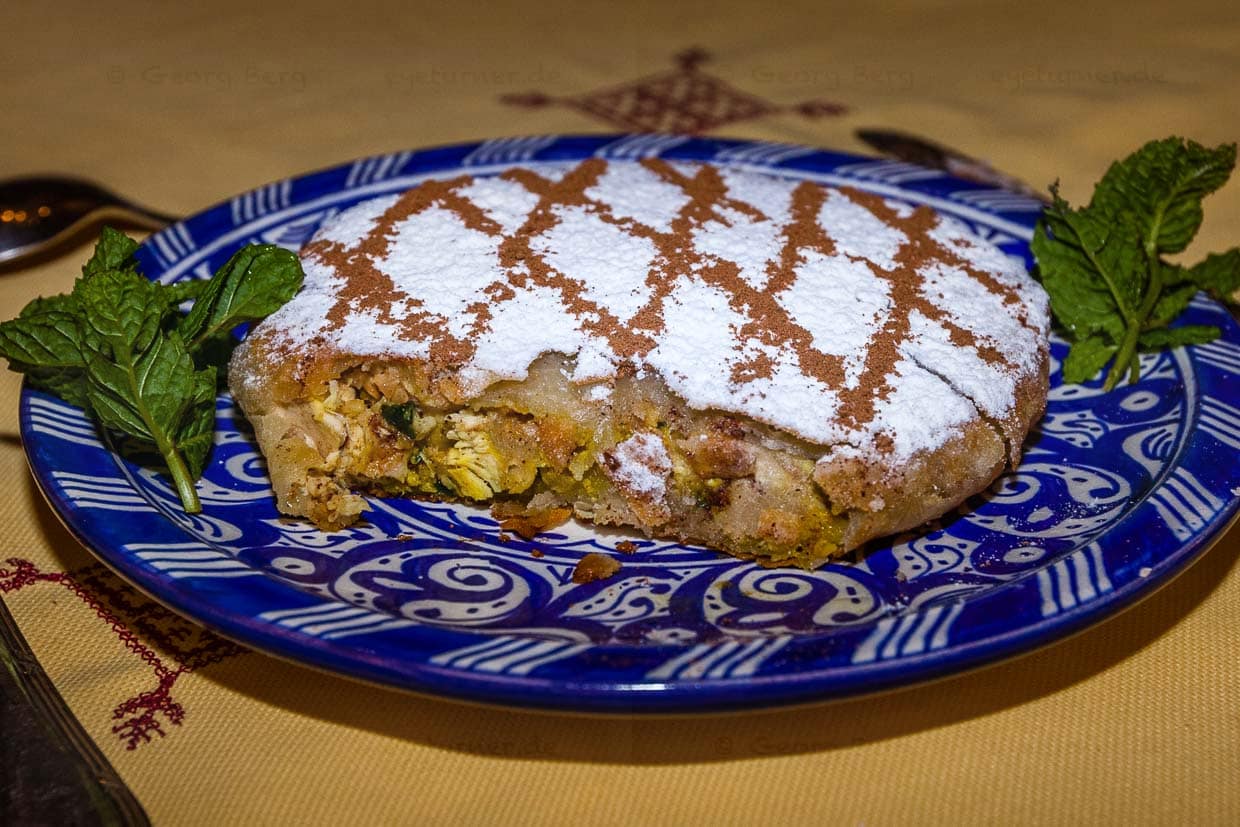 Eine in Marokko Pastilla genannte Blätterteigpastete bildet die Vorspeise. Bei einer angenehm milden Zimtanmutung verträgt sich das Hühnerfleisch erstaunlich gut mit den untergehobenen Eiern, mit Petersilie, Zwiebeln, Mandeln und Ingwer / © Foto: Georg Berg