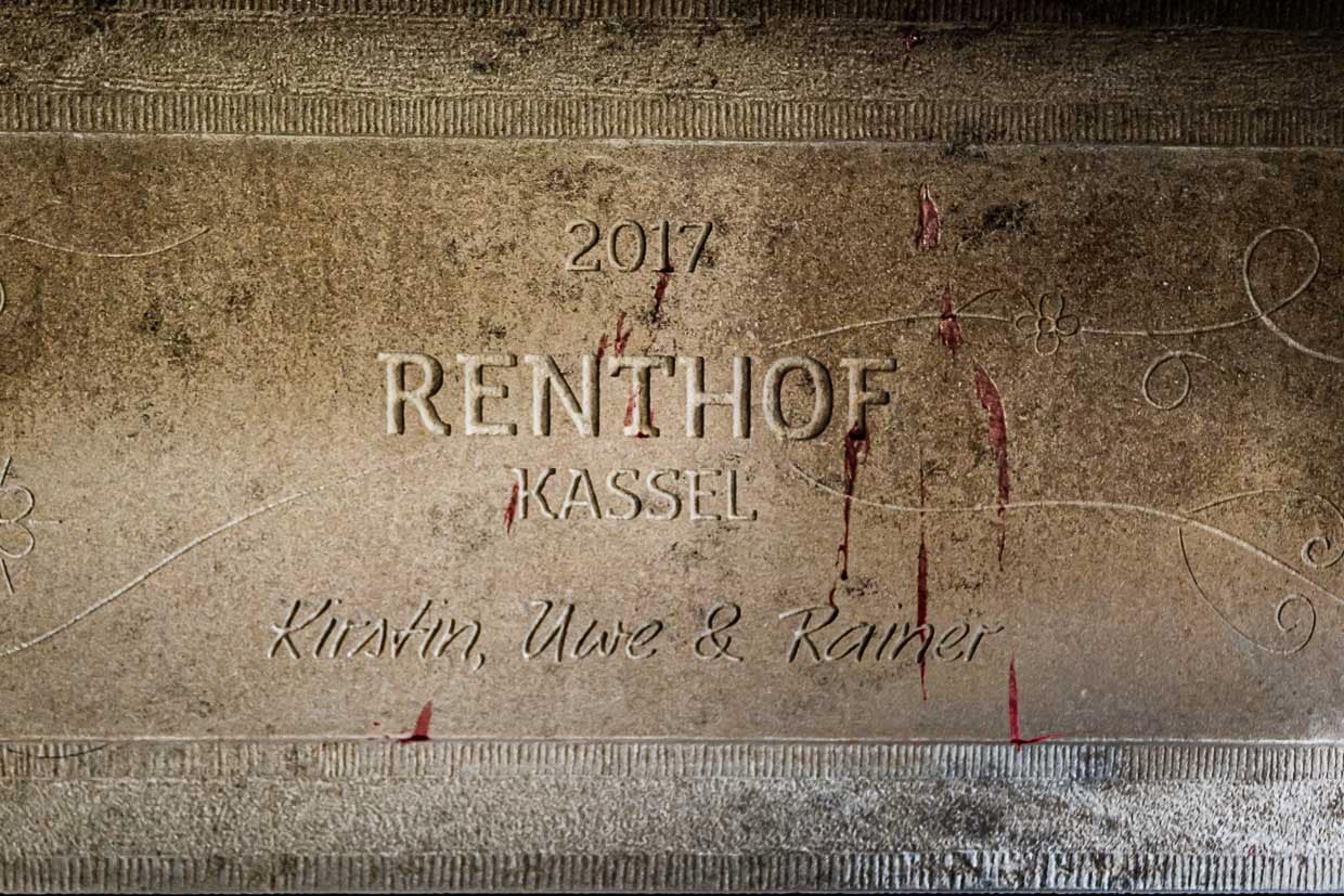 Die Verantwortlichen für das unkonventionelle Gesamtwerk Renthof, in dem der Gast nicht weniger als den Zustand des Pudelwohlfühlens erreichen soll, sind auf dem Kamin in Stein gemeißelt: Kirstin, Uwe und Rainer / © Foto: Georg Berg