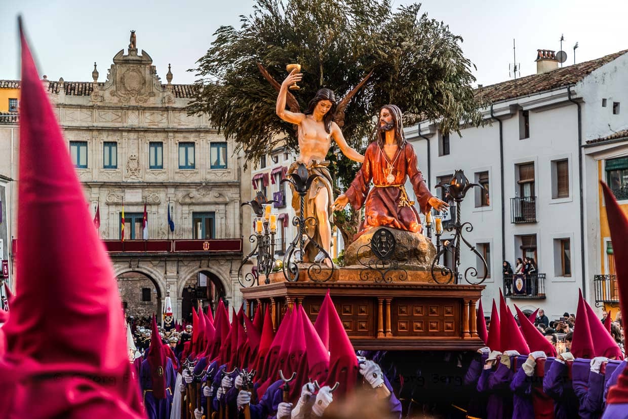 Procession in Spain with Jesus and an angel on a float; pilgrims wear red and purple robes / © Photo: Georg Berg