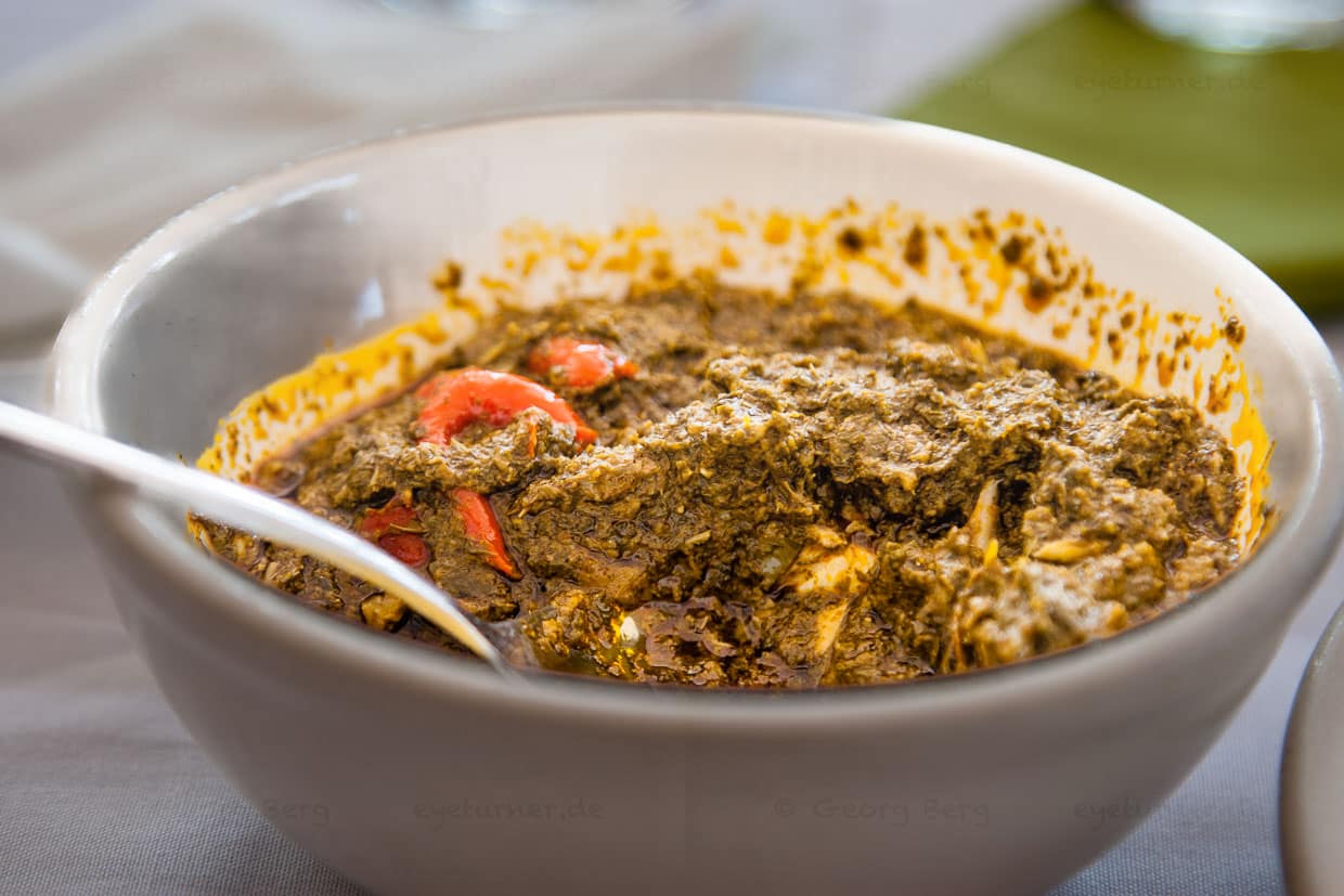 In ihrer Konsistenz gleicht die beliebte scharfe Cassava-Soße püriertem Spinat. Abgebildet ist eine Restaurant-Portion. Hausgemeinschaften essen in Sierra Leone üblicherweise gemeinsam aus einer Schüssel / © Foto: Georg Berg