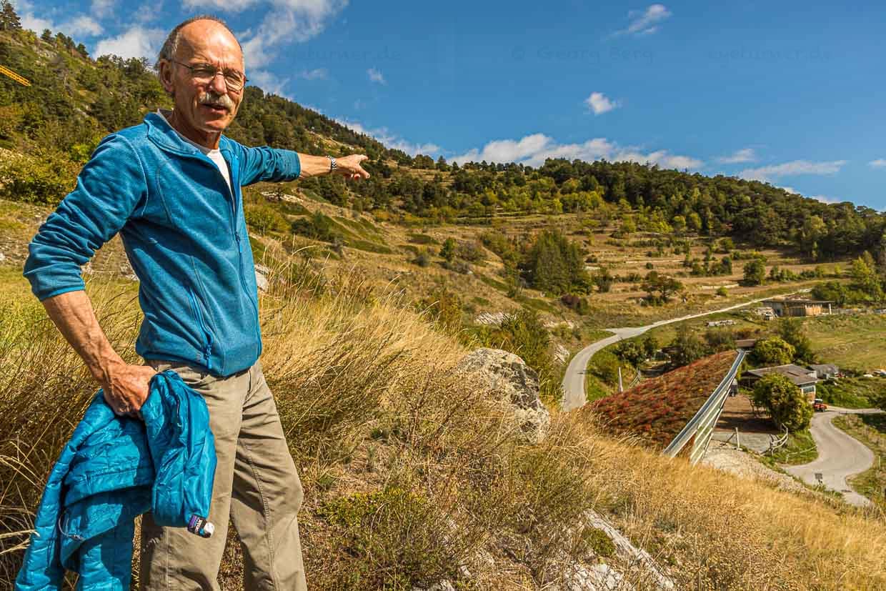 Edmund Steiner zeigt auf die Roggenfelder oberhalb von Erschmatt. Jahrhundertelang ist Walliser Roggen auf den Terrassen angebaut worden. Ein Rundgang durchs Dorf samt anschaulicher Schilderungen über das harte Leben damals, gehört mit zum Workshop Roggenbrot backen / © Foto: Georg Berg