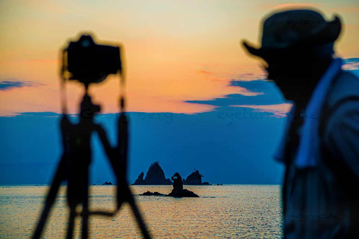 Am Strand der Tago Bay bringen sich abends unzählige Sonnenuntergangs-Fotografen in Stellung und warten auf den Augenblick, in dem sich der Sonnenball für einen kurzen Moment wie ein Edelstein in die natürliche und runde Aussparung der Felsen schiebt / © Foto: Georg Berg