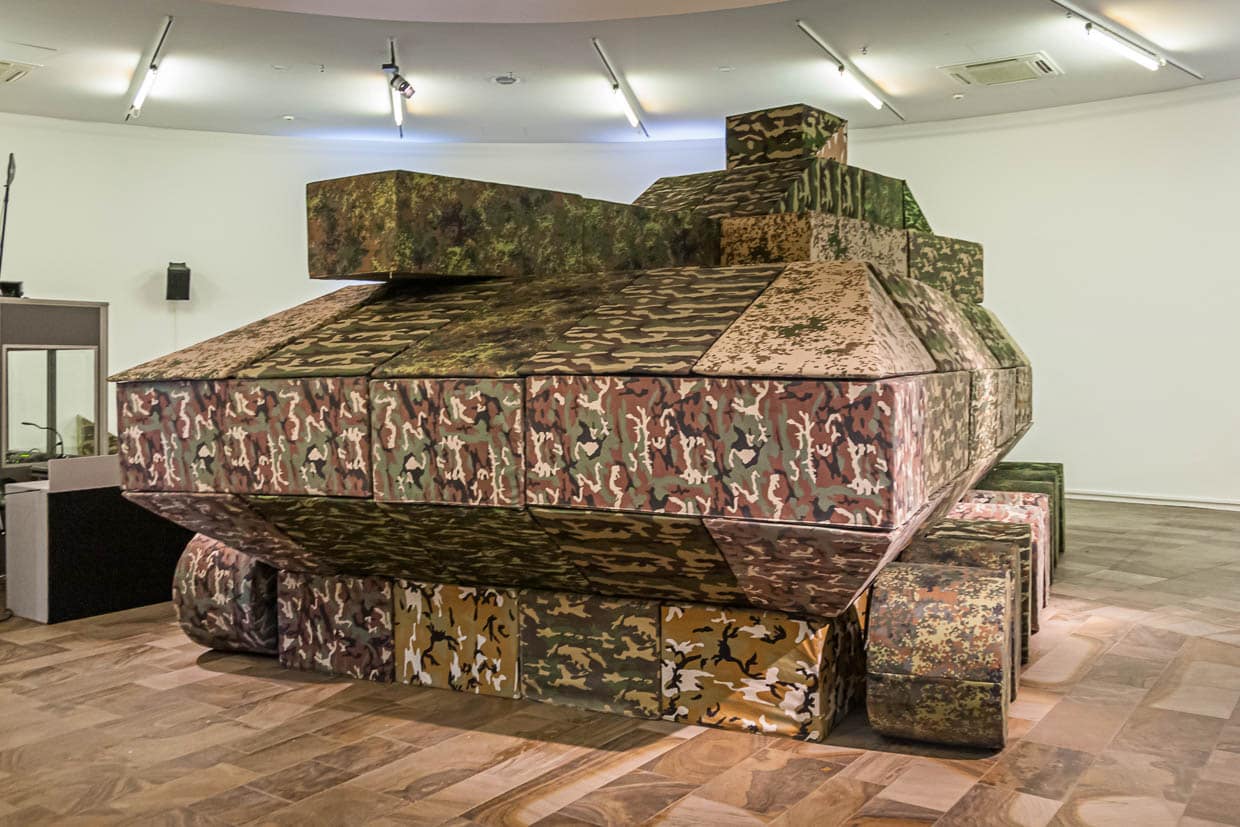 La guerre - un thème récurrent à la documenta. Des modules de sièges en camouflage de taches sont assemblés deux fois par semaine lors d'une performance pour former un char d'assaut grandeur nature / © Photo : Georg Berg
