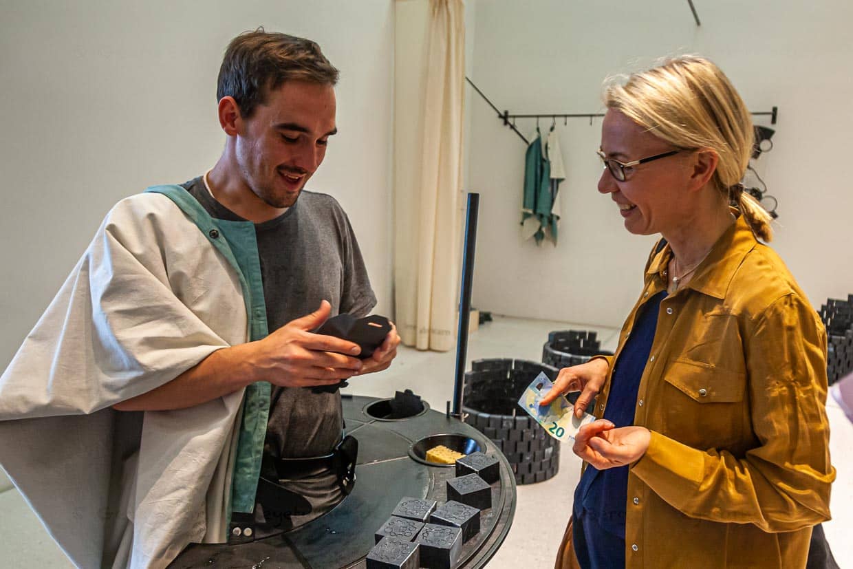 Mitten im Verkaufsgespräch: Angela Berg fragt Kunststudenten Viktor nach den 7 Ölen der Seife von Künstlerin Otobong Nkanga / © Foto: Georg Berg