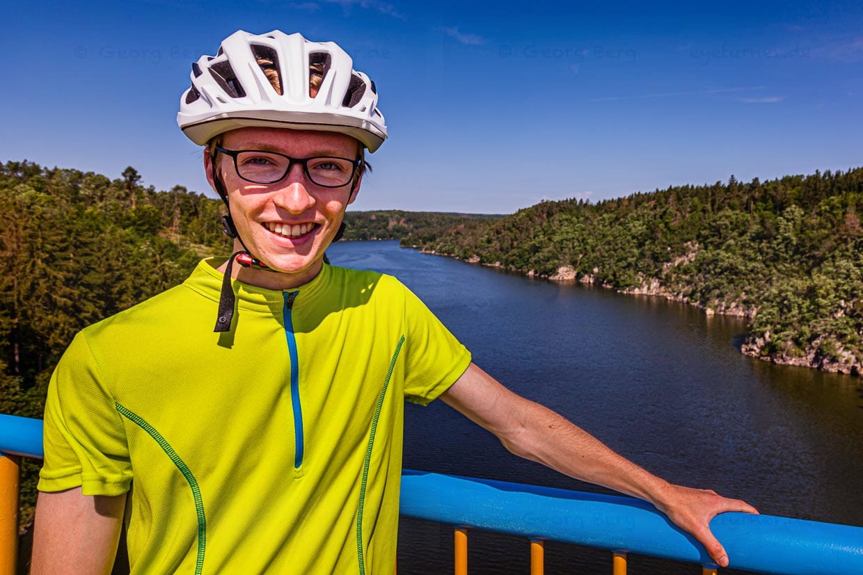 Julius Berg auf einer Moldaubrücke. Das Ufer ist über weite Strecken im ursprünglichen Zustand und die meisten Radwege führen über das hügelige Hinterland / © Foto: Georg Berg