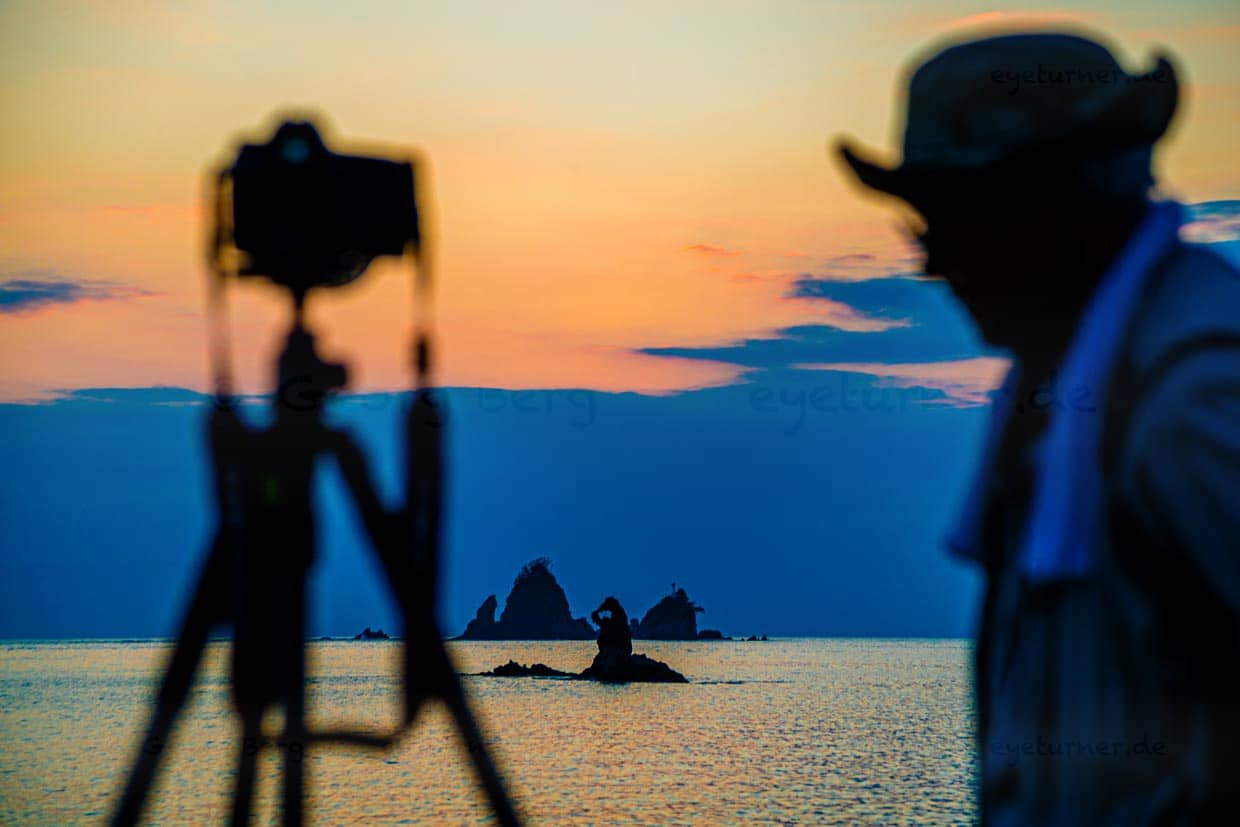Am Strand der Tago Bay bringen sich abends unzählige Sonnenuntergangs-Fotografen in Stellung und warten auf den Augenblick, in dem sich der Sonnenball für einen kurzen Moment wie ein Edelstein in die natürliche und runde Aussparung der Felsen schiebt / © Foto: Georg Berg