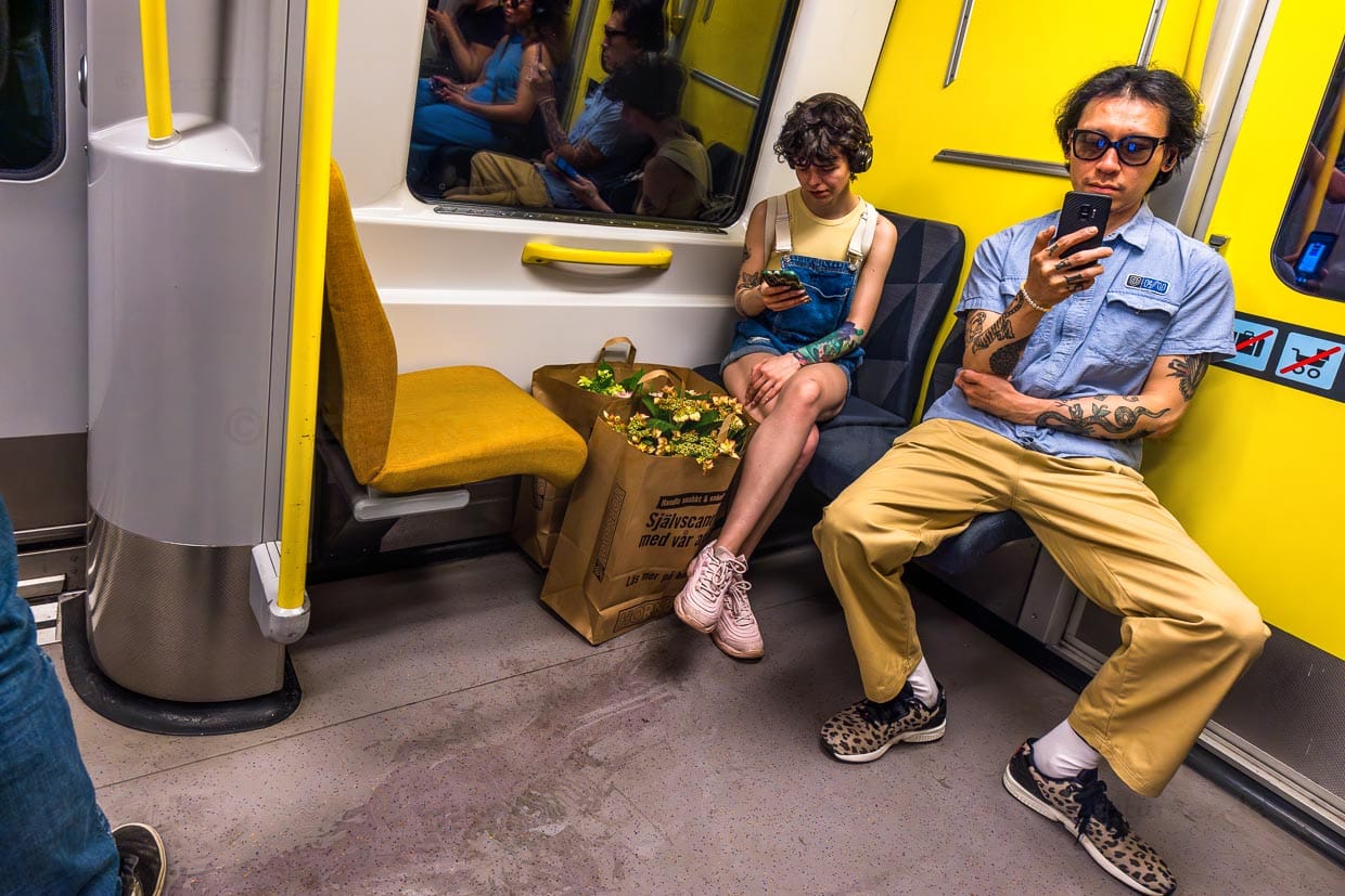 Manchmal sehen auch die Fahrgäste, wie ein komponiertes Kunstwerk aus: hier junges Paar in der Metro Stockholm mit Mobiltelefon in der Hand, Tatoos auf den Armen und Blumen in der Einkaufstasche / © Foto: Georg Berg