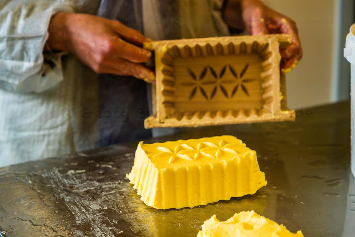 Goldgelbe Almbutter wird in mit Hilfe einer traditionellen Holzform portioniert / © Foto: Georg Berg