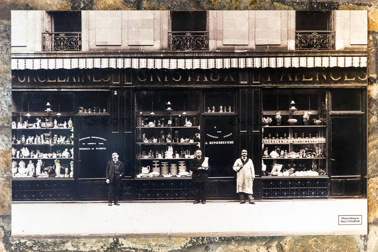 Alte Postkarte aus dem Museum Four des Casseaux in Limoges zeigt ein Foto von Paul Colmar: Porzellanhändler vor den Schaufenstern ihres Geschäfts mit Porzellanfiguren und Haushaltswaren aus Porzellan / © Foto: Georg Berg