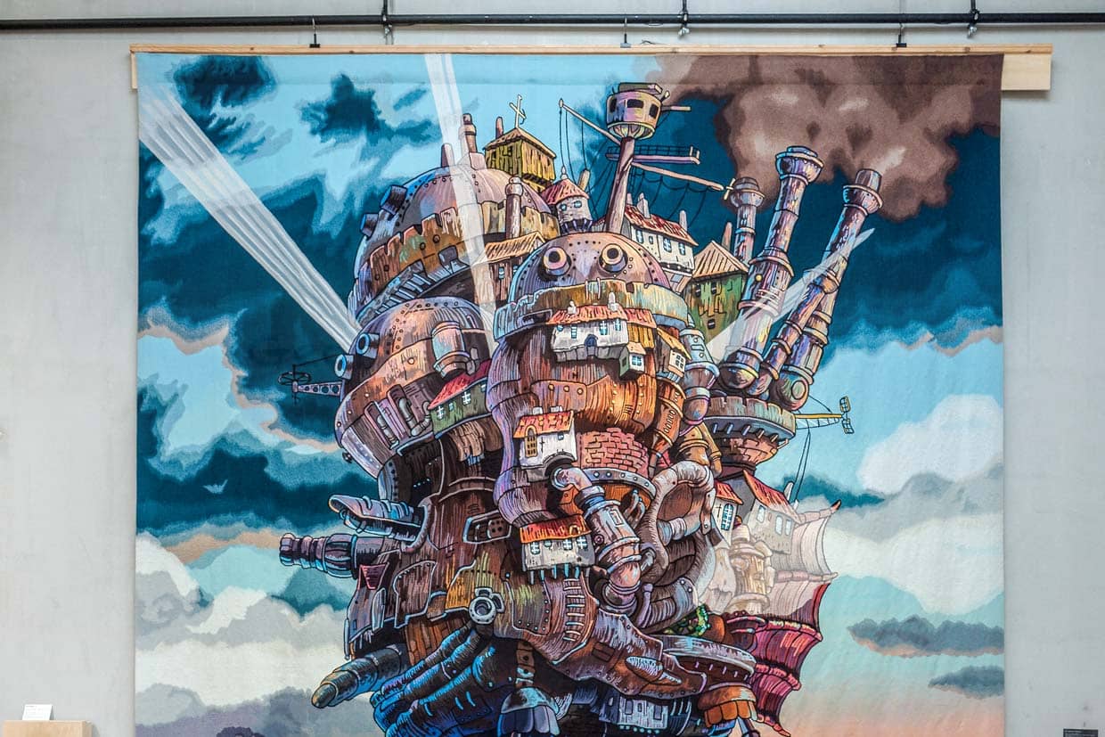 Gewebte Abenteuer in den Ausstellungsräumen der Cité internationale de la tapisserie Aubusson. Hier „The moving castle at sunset“  aus dem Animefilm von 2004 Howl’s Moving Castle. Gewebt in Aubusson ab März 2022 bis Februar 2023 / © Foto: Georg Berg