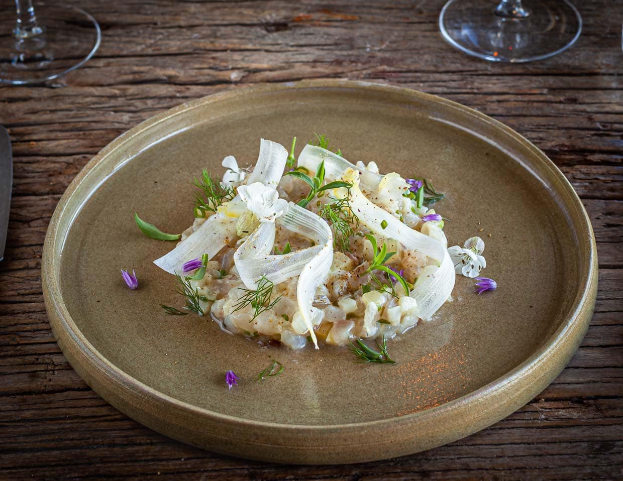 Die marinierte Seebrasse wird mit frisch gesammelten Kräutern von der nahe gelegenen Meeresklippe angerichtet / © Foto: Georg Berg