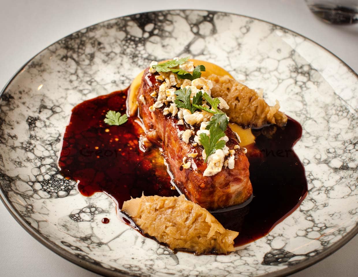 Fleisch vom Schweinefuß kombiniert mit Sauerkraut und Erbsenpüree und einer malzigen Dunkelbiersauce. Das Topping besteht aus gepoppter Schweinehaut / © Foto: Georg Berg