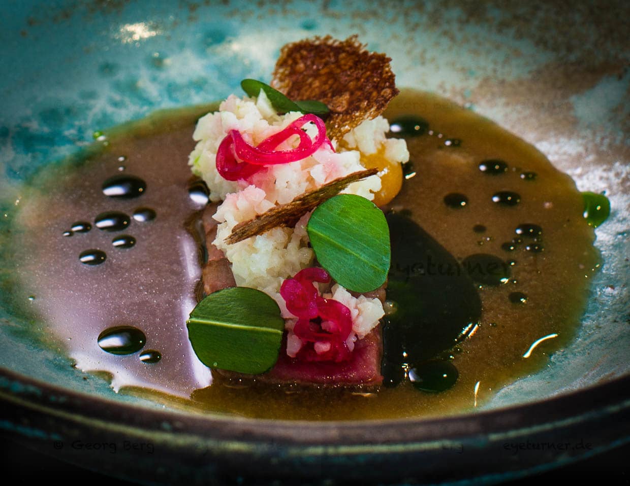 Schweinebauch mit Blumenkohlcouscous in Gerstenmiso-Sud und Bärlauchöl / © Foto: Georg Berg