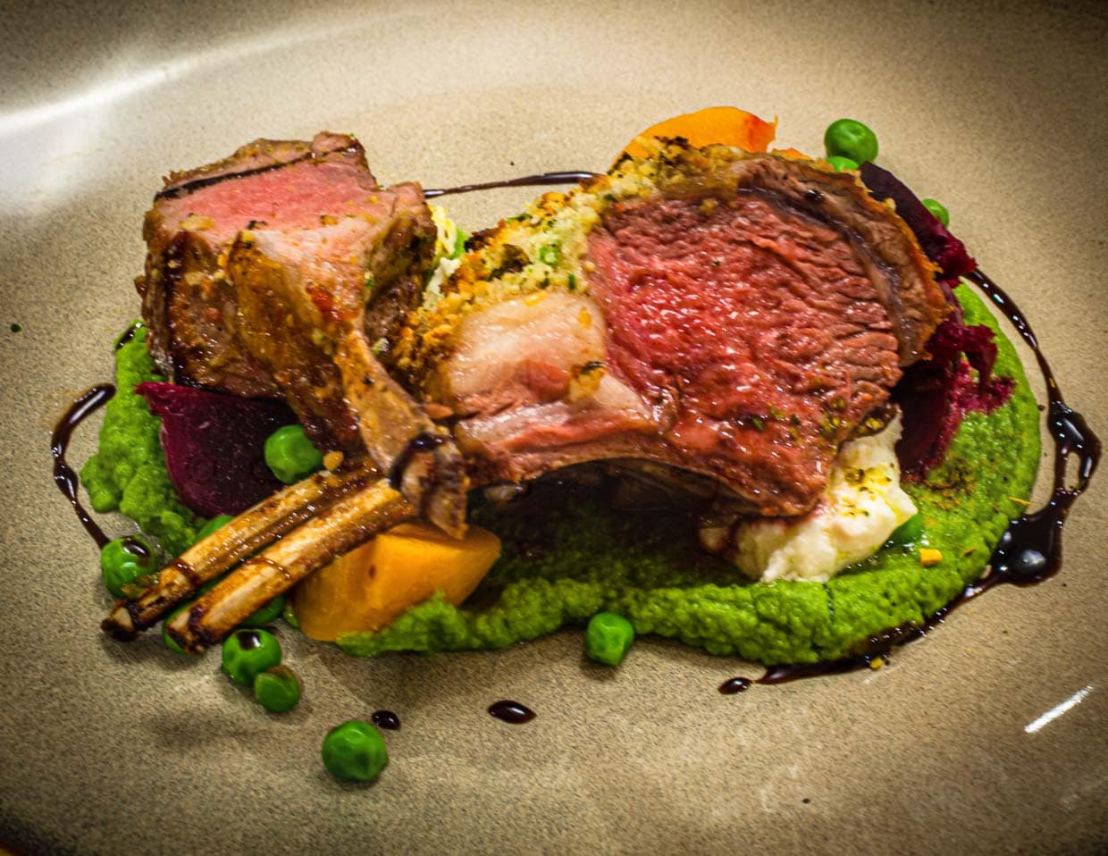 Und so kommt es dann köstlich mit tasmanischem Pfeffer und Vincotto gewürzt auf den Tisch: Lammkarree in der Pinienkruste mit Schafskäse an Erbsen-Mint-Püree / © Foto: Georg Berg